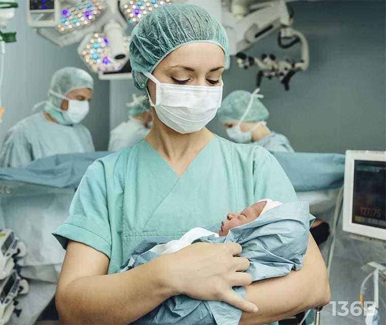 Leben mit ITP: Eine OP-Schwester hält einen Säugling im Arm